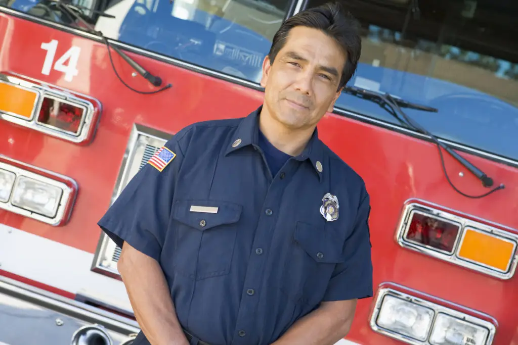 A proud firefighter standing in front of a fire engine, ready to serve and protect the community.