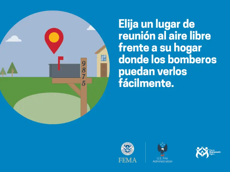 Un cartel informativo en español que aconseja elegir un lugar de reunión al aire libre donde los bomberos puedan ver a las personas fácilmente en caso de emergencia, ilustrado con un marcador de ubicación rojo sobre un fondo de paisaje con una casa y árboles. logotipos de fema, us fire administration y ready.gov aparecen en la parte inferior.