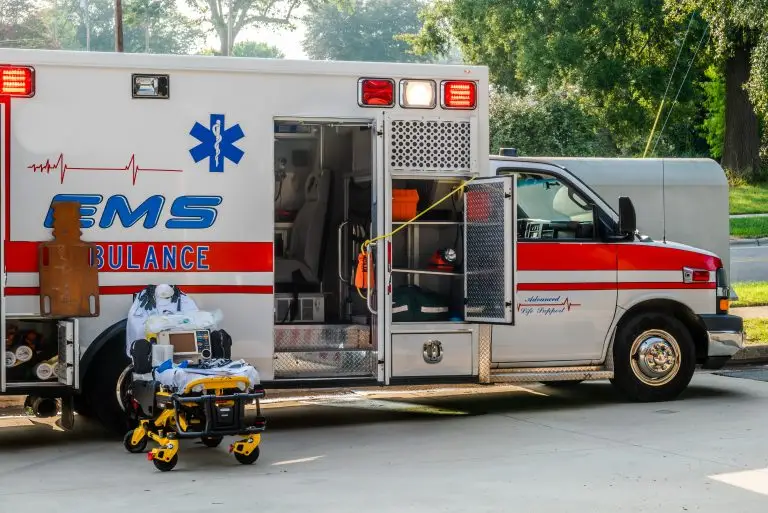 An ambulance parked with its back doors open, revealing medical equipment and a stretcher ready for emergency response.